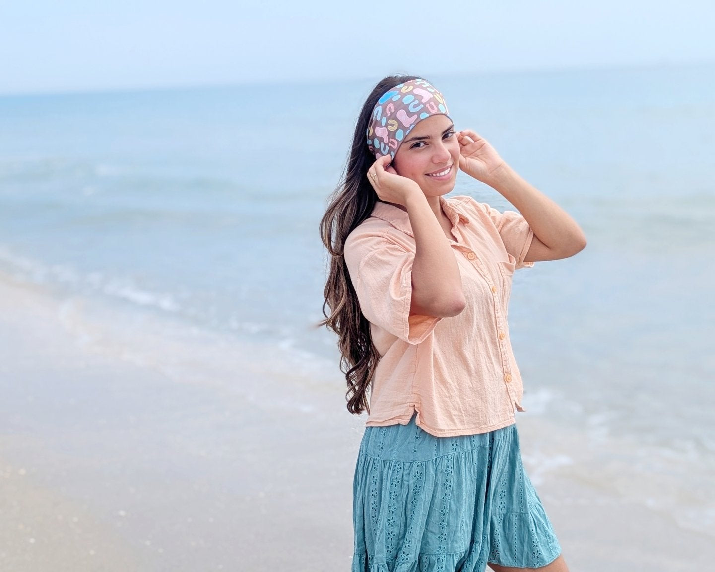 Woman on a beach wearing a colorful headband and light clothing