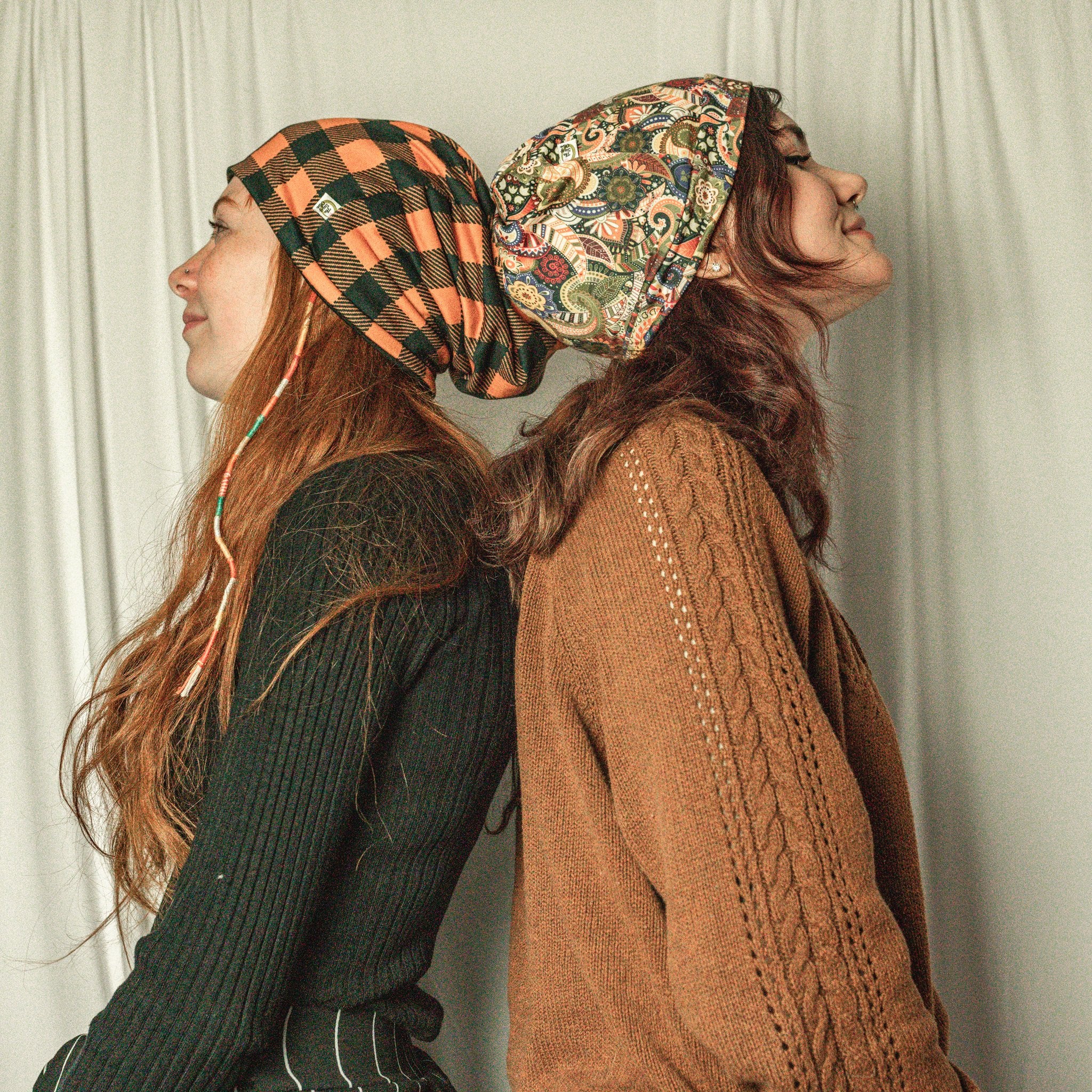 Two women wearing patterned headscarves against a plain background
