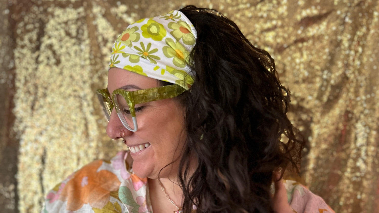 Woman wearing a floral headband and sunglasses with a gold leaf pattern against a textured gold background