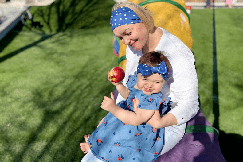 Woman holding a baby outdoors on a sunny day